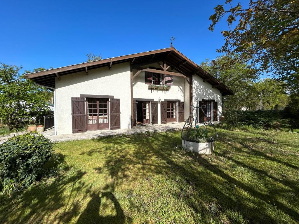 une petite maison blanche avec une grande pelouse dans l'établissement Maison de famille Basque, à Soulac-sur-Mer