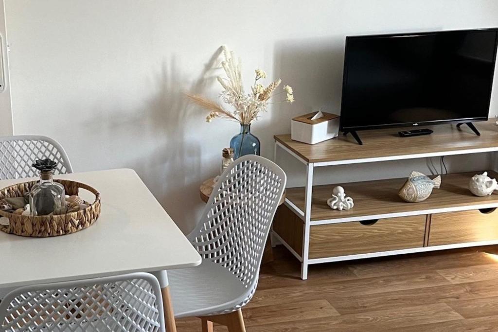 un salon avec une télévision, une table et des chaises dans l'établissement Quiet T2 near the beach in Villers-sur-Mer, à Villers-sur-Mer