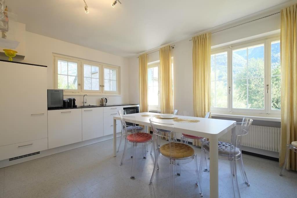 a white kitchen with a white table and chairs at Appartement da Käthy à Grono Val Mesolcina in Grono