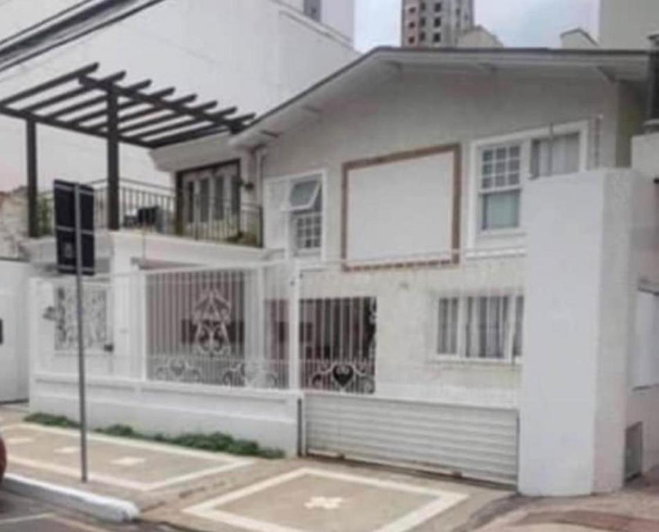 une maison blanche avec un panneau publicitaire sur le côté dans l'établissement Casa Charmosa Centro Balneário Camboriú, à Balneário Camboriú