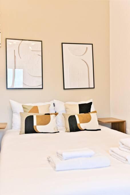 - une chambre avec un lit blanc et des oreillers dans l'établissement Petit Studio chaleureux en Banlieue - Asnières, à Asnières-sur-Seine