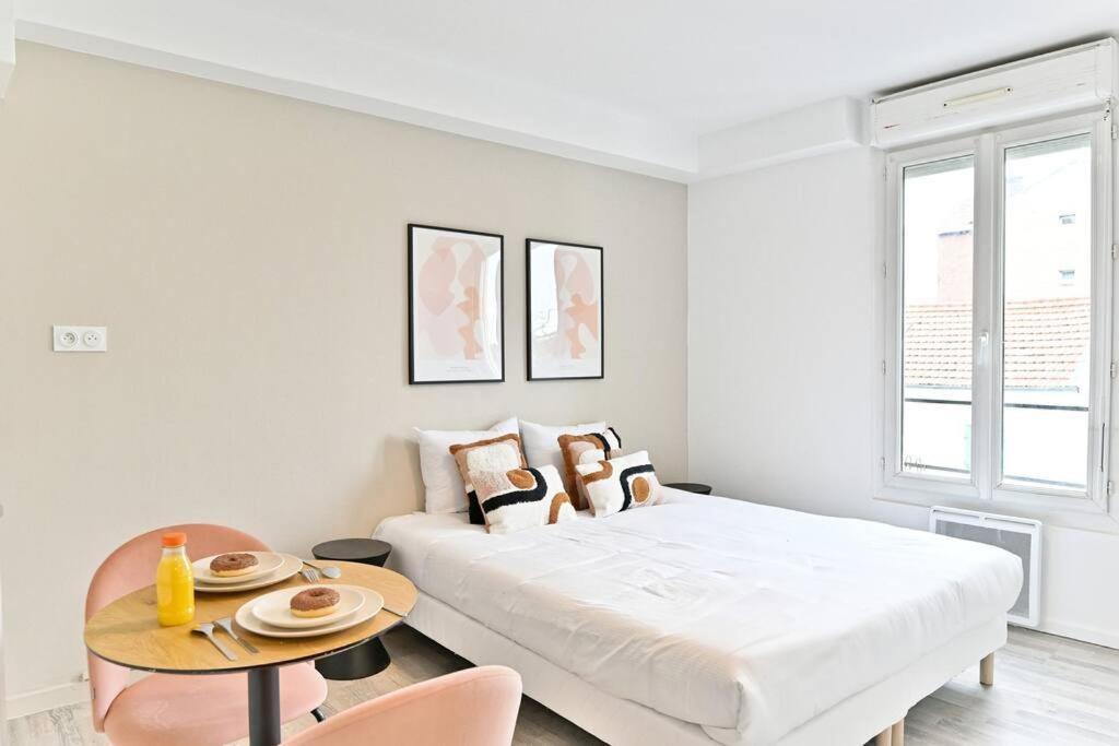 une chambre blanche avec un lit et une table dans l'établissement Petit studio équipée en banlieue Parisienne, à Asnières-sur-Seine
