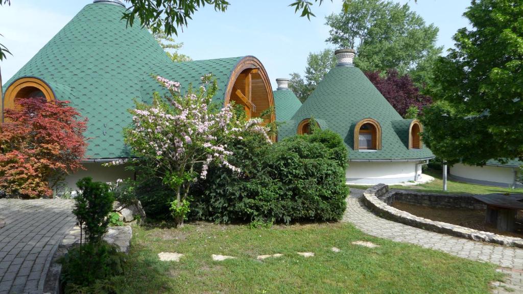 ein Haus mit einem grünen Dach und einem Garten in der Unterkunft Gesztenye Nyaralópark in Balatonudvari