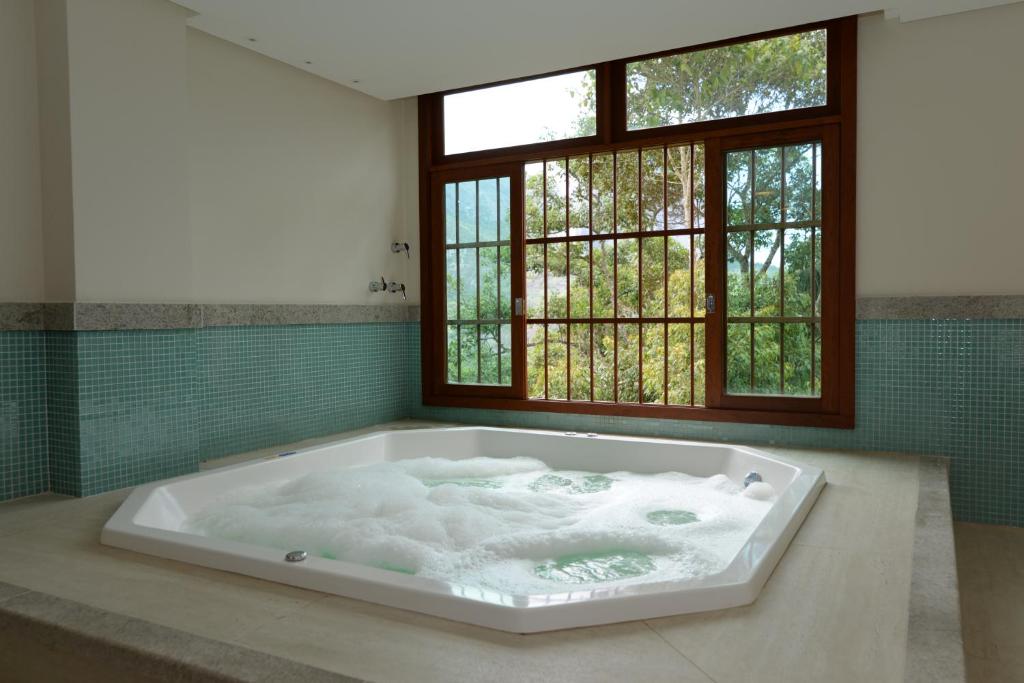 una grande vasca da bagno in una stanza con finestra di Vista Azul Apart Hotel - Pedra Azul pinheiros a Pedra Azul