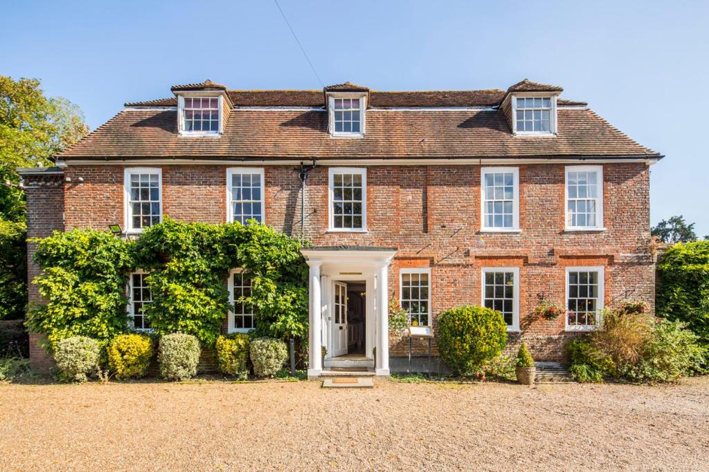 uma velha casa de tijolos vermelhos com uma porta branca em Flackley Ash Country House Hotel em Rye