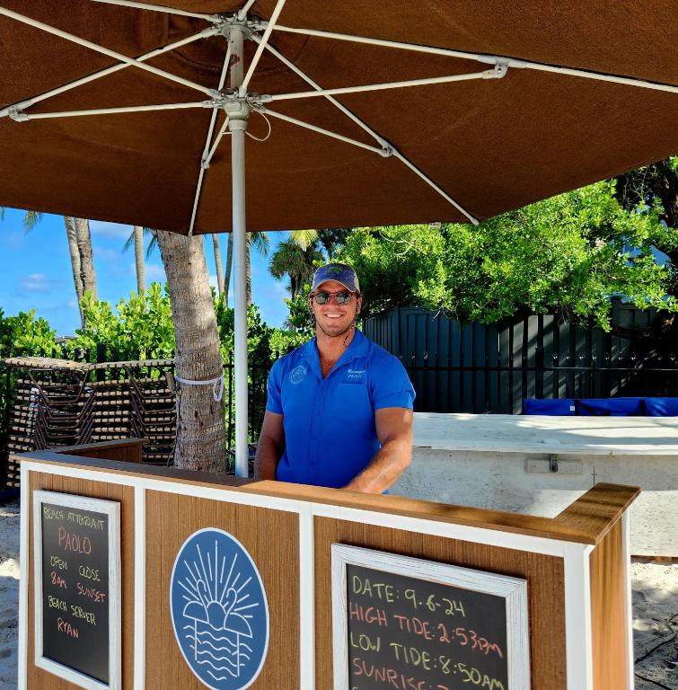 a man standing behind a food cart under an umbrella at Vanderbilt Beach Resort in Naples