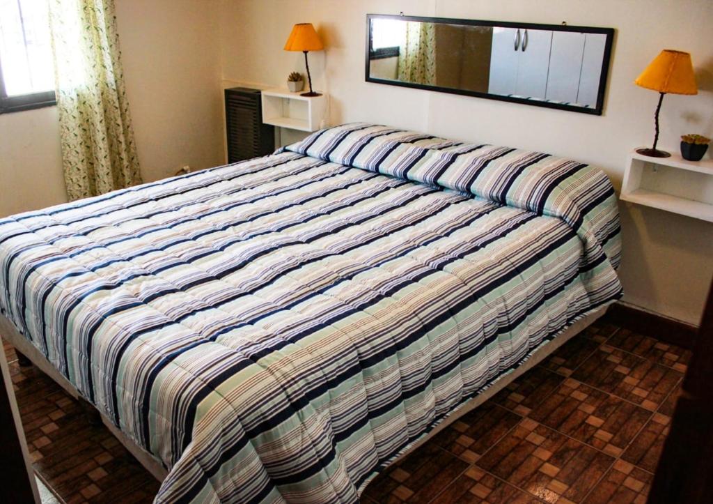1 dormitorio con 1 cama con edredón a rayas en Dulce Hogar, en Mendoza