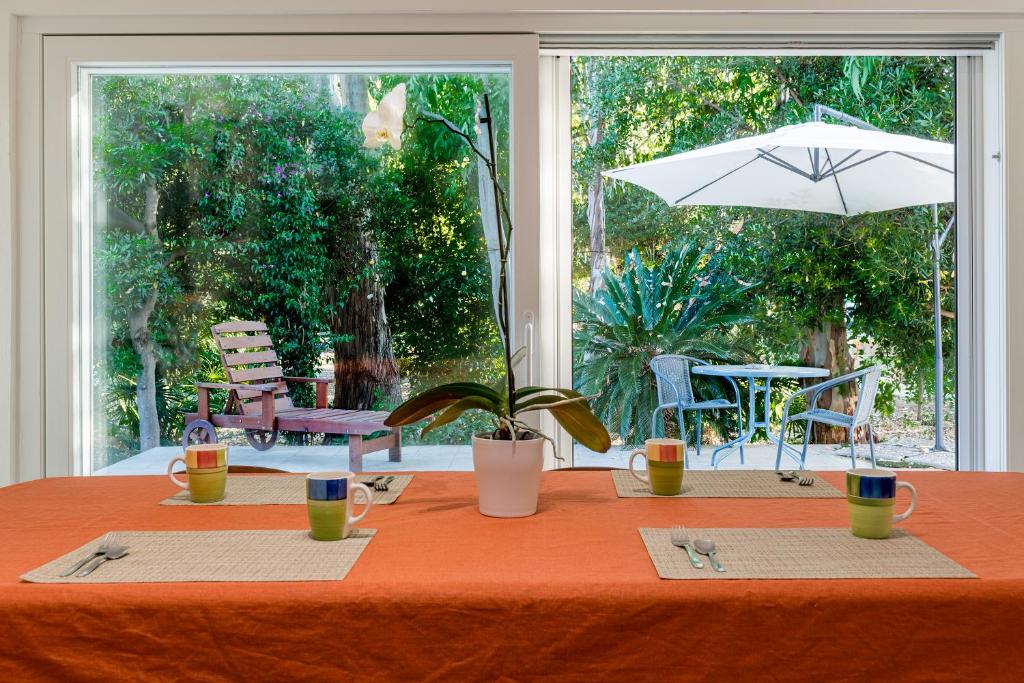 Una mesa con un mantel naranja y una sombrilla. en Villa Eucalipti sul mare, en Bari
