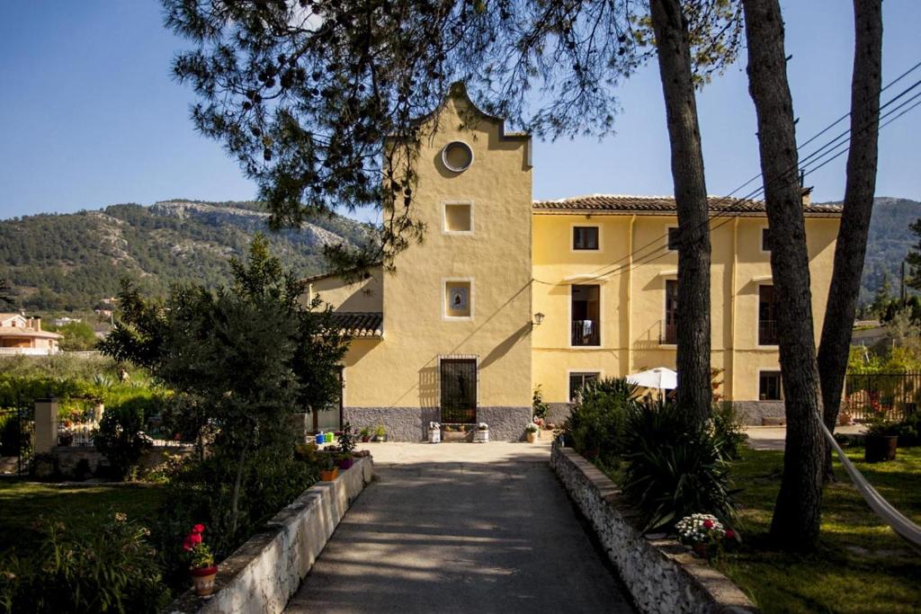 un grand bâtiment jaune avec une tour d'horloge dans l'établissement Villa Carmen, à Bocairent