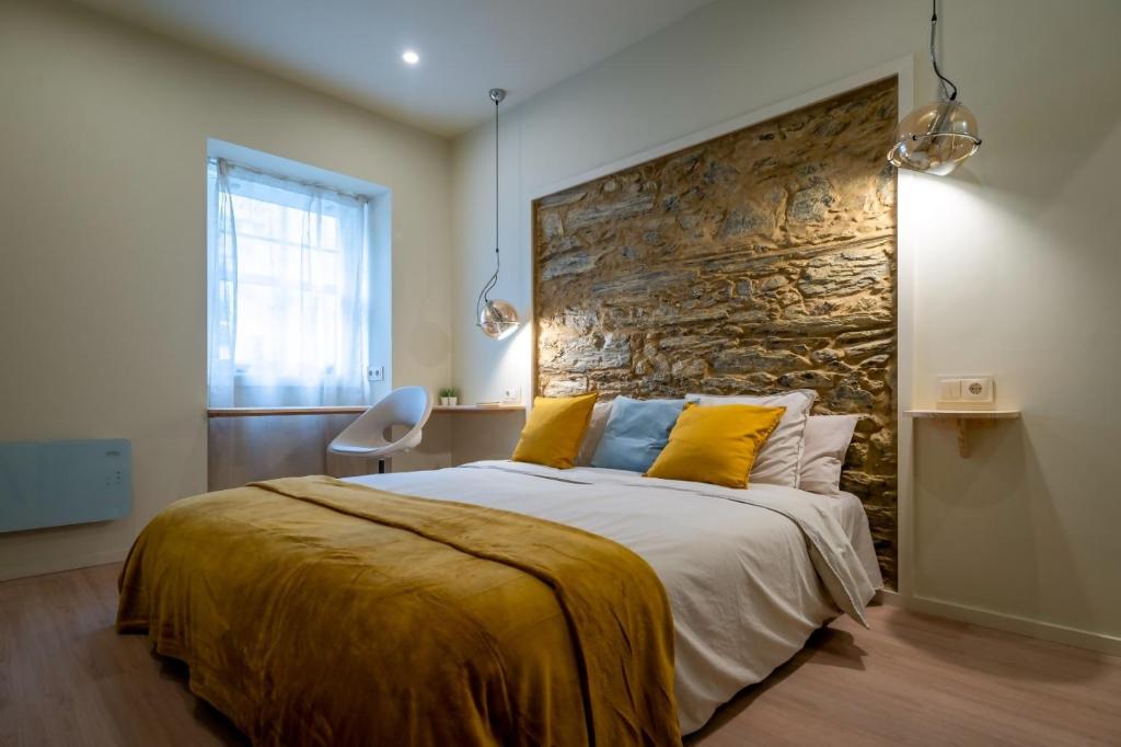 a bedroom with a large bed with a stone wall at Miña Nai Apartment in Ferrol