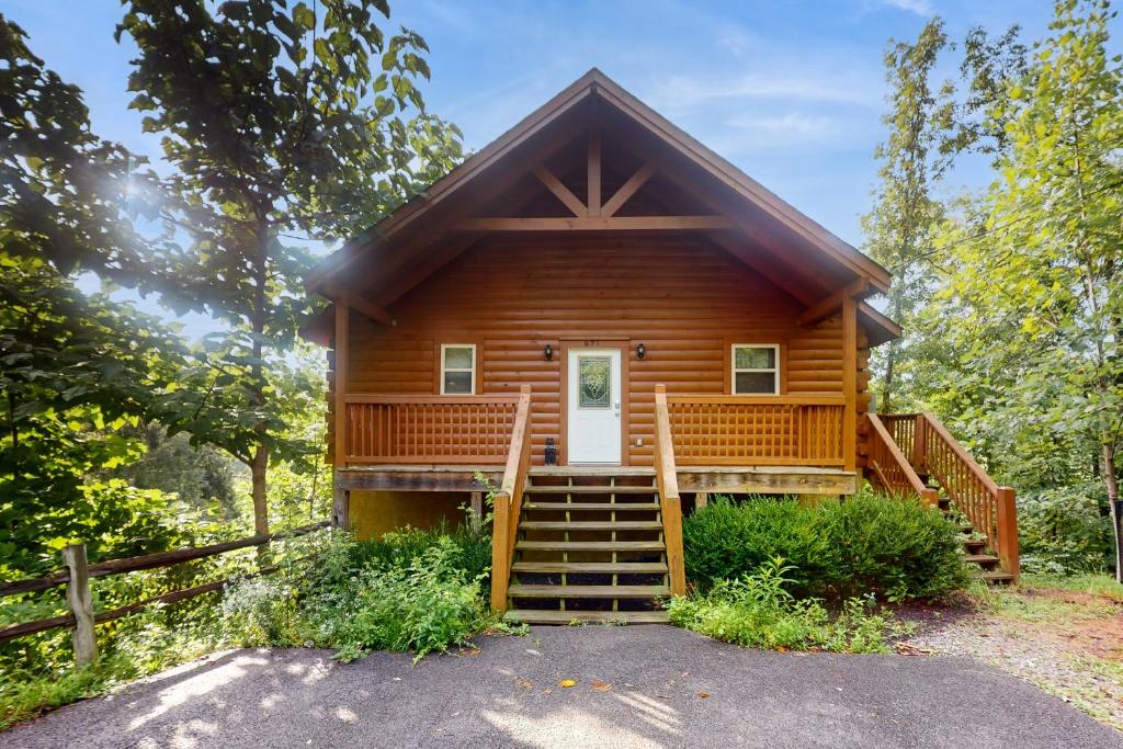 une cabane en rondins dans les bois avec une terrasse couverte et des escaliers dans l'établissement Deer Pass Lodge, à Pigeon Forge