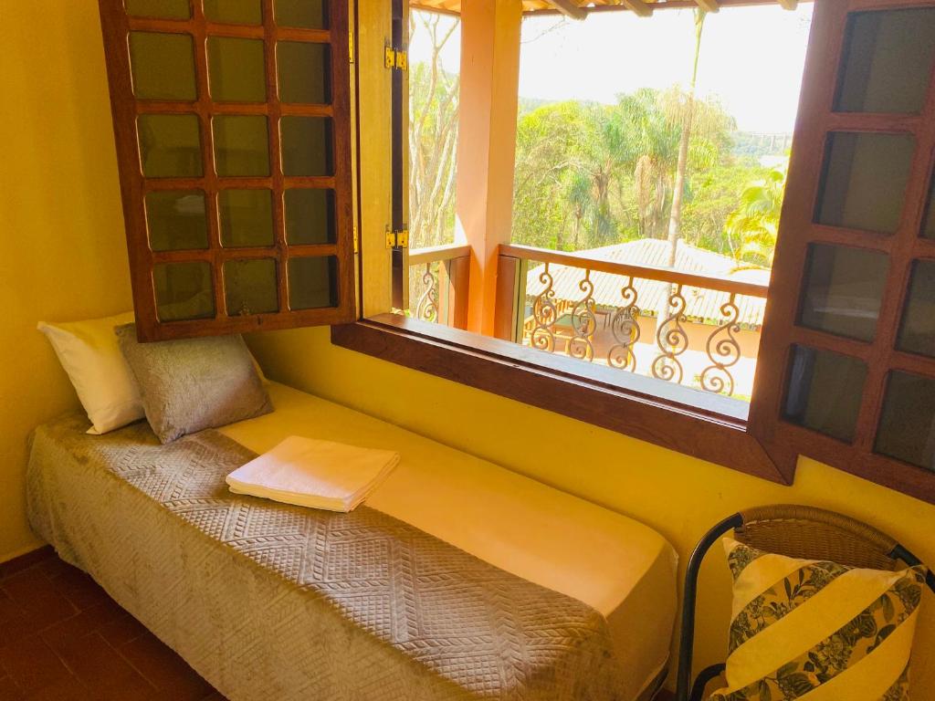 a bench in a room with a window with a book at Hospedaria Casa dos Coqueiros in Itabirito