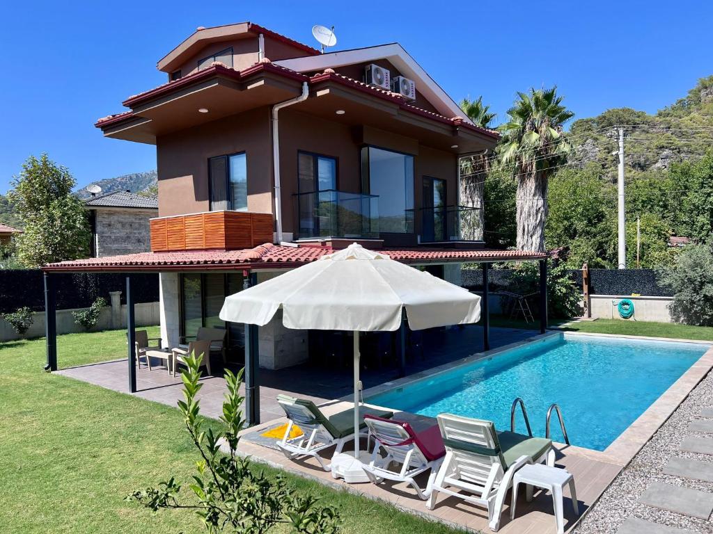a house with a swimming pool with chairs and an umbrella at Göcek Villa Hayal in İnlice