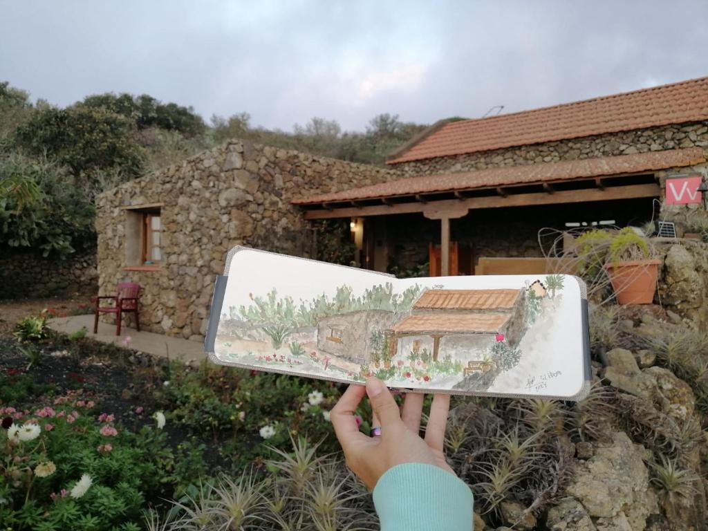 a person holding up a picture of a house at El Pajero de Erese in Erese