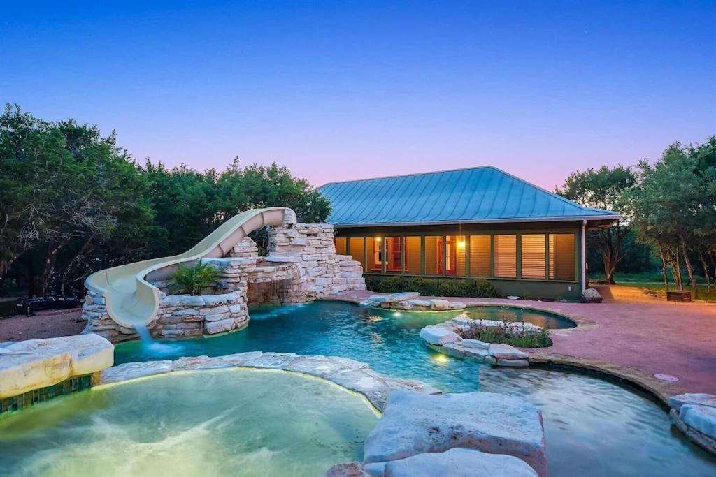 a pool with a water slide in a backyard at Grit&Grace Ranch - Private Resort Style Pool & Spa in Bee Cave