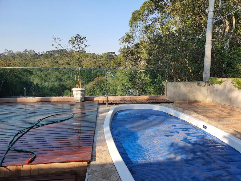 a swimming pool with a hose on a wooden deck at Chácara c piscina in Cotia