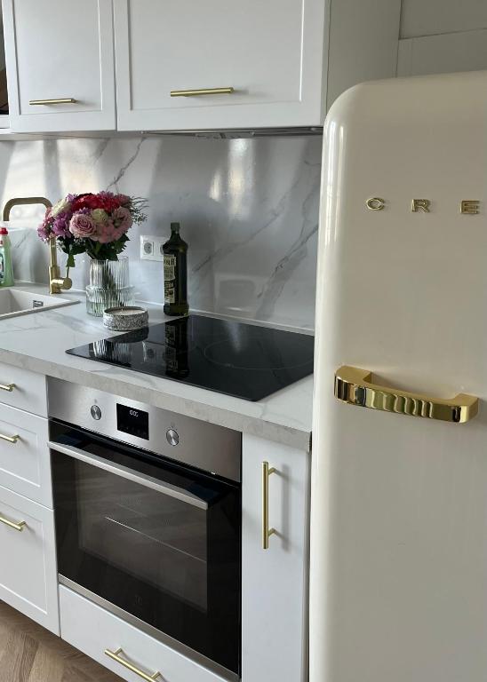 Il comprend une cuisine blanche équipée d'une cuisinière et d'un réfrigérateur. dans l'établissement Appartement au cœur de Paris, à Paris