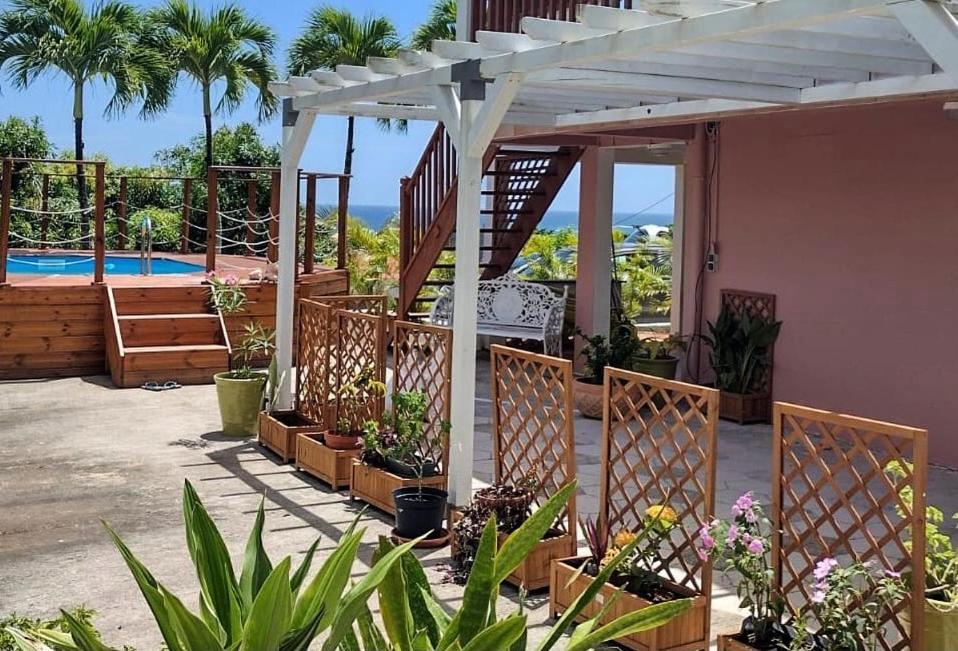 ein Haus mit einer weißen Pergola und einigen Pflanzen in der Unterkunft La Canopée - Appartement F2 avec piscine - vue mer in Le Robert