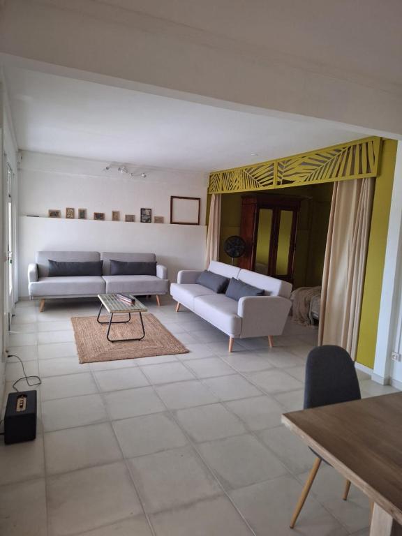 ein Wohnzimmer mit zwei Sofas und einem Tisch in der Unterkunft La Canopée - Appartement F2 avec piscine - vue mer in Le Robert