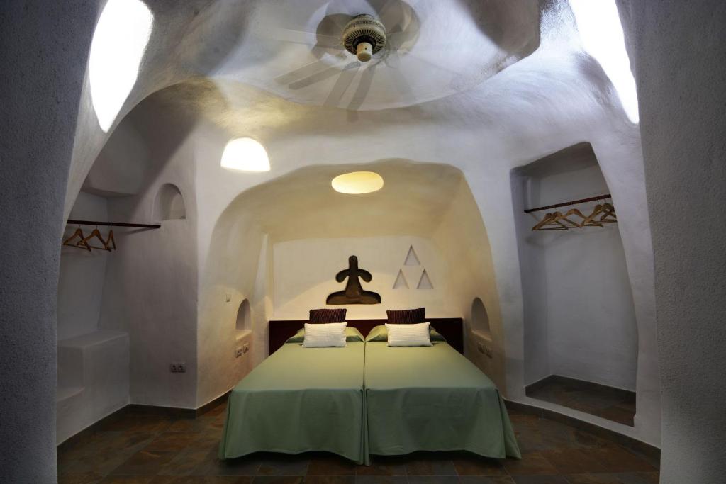 a bedroom with a bed with a green blanket at Cuevas De Barreto in Firgas