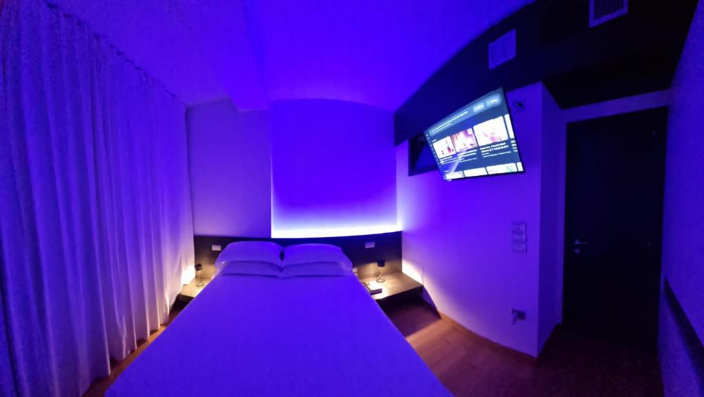 a purple room with a bed and a tv at Attico Reale - in Centro, tra Stazione e Bari Vecchia in Bari