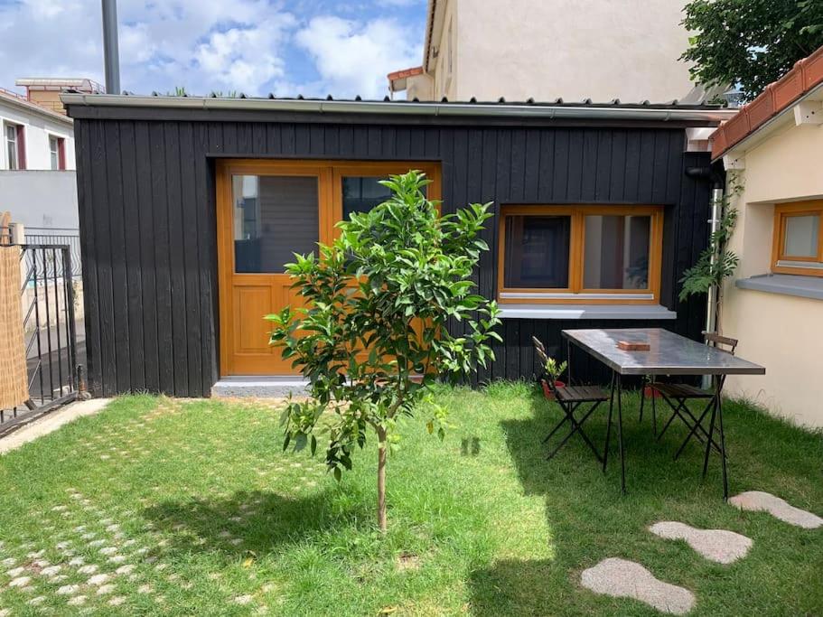 une petite maison noire avec une table dans la cour dans l'établissement Grand Studio, à Romainville