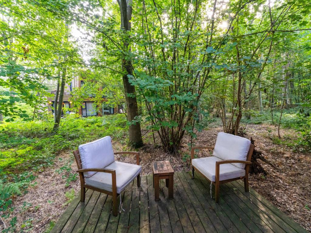 two chairs and a table on a deck with trees at Cottage in Antoing, Hainaut in Antoing