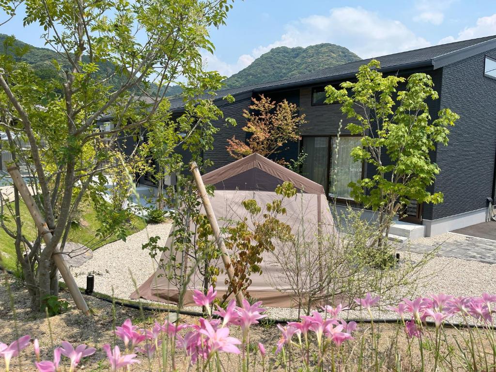 a garden with pink flowers in front of a house at ふぁーむふぁーむ in Miyaji