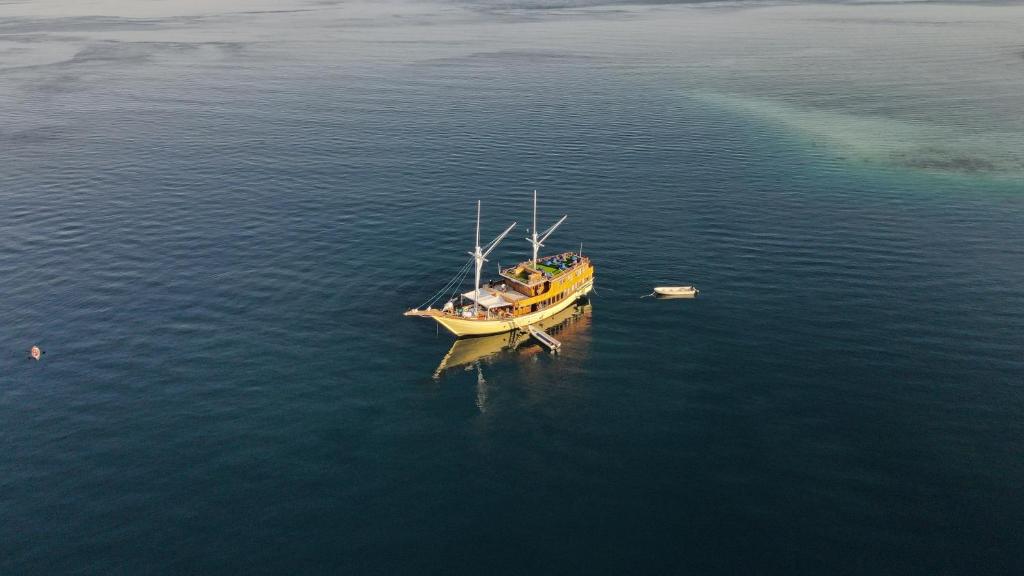een gele boot die midden op het water ligt bij Leticia Liveaboard in Labuan Bajo