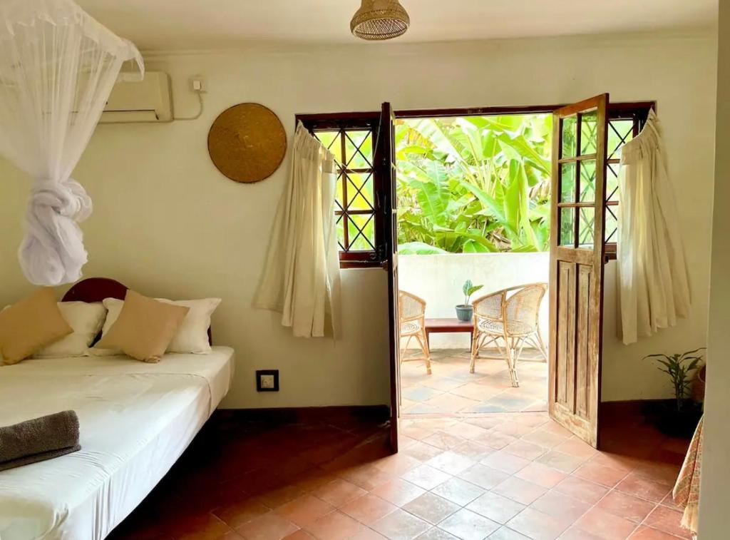 Un dormitorio con una cama y una puerta a un patio. en Blue Swan Inn, en Unawatuna