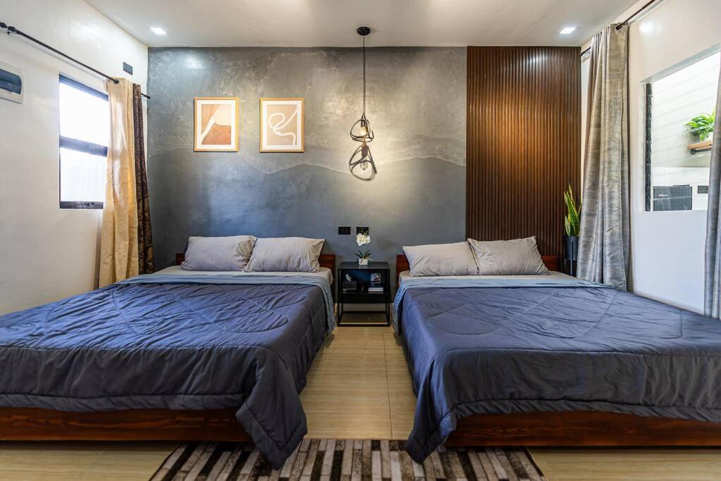 two beds in a bedroom with blue sheets at Industrial Themed House in General Santos City in General Santos