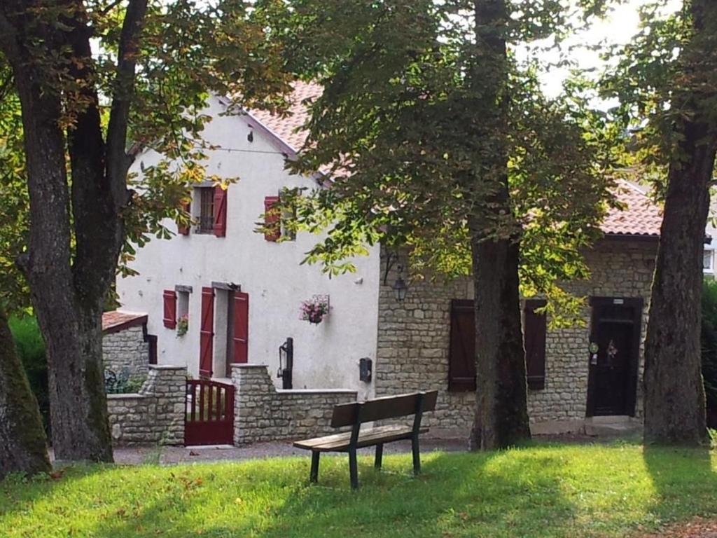 a bench sitting in front of a white house at Charmante maison historique avec jardin à Vadelaincourt - Charme, cheminée, et sérénité - FR-1-585-67 in Vadelaincourt
