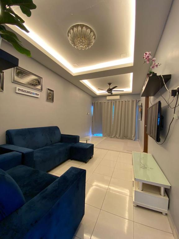 Teratak Raffa Homestay في Kampong Tebing Rabak: غرفة معيشة مع أريكة زرقاء وتلفزيون