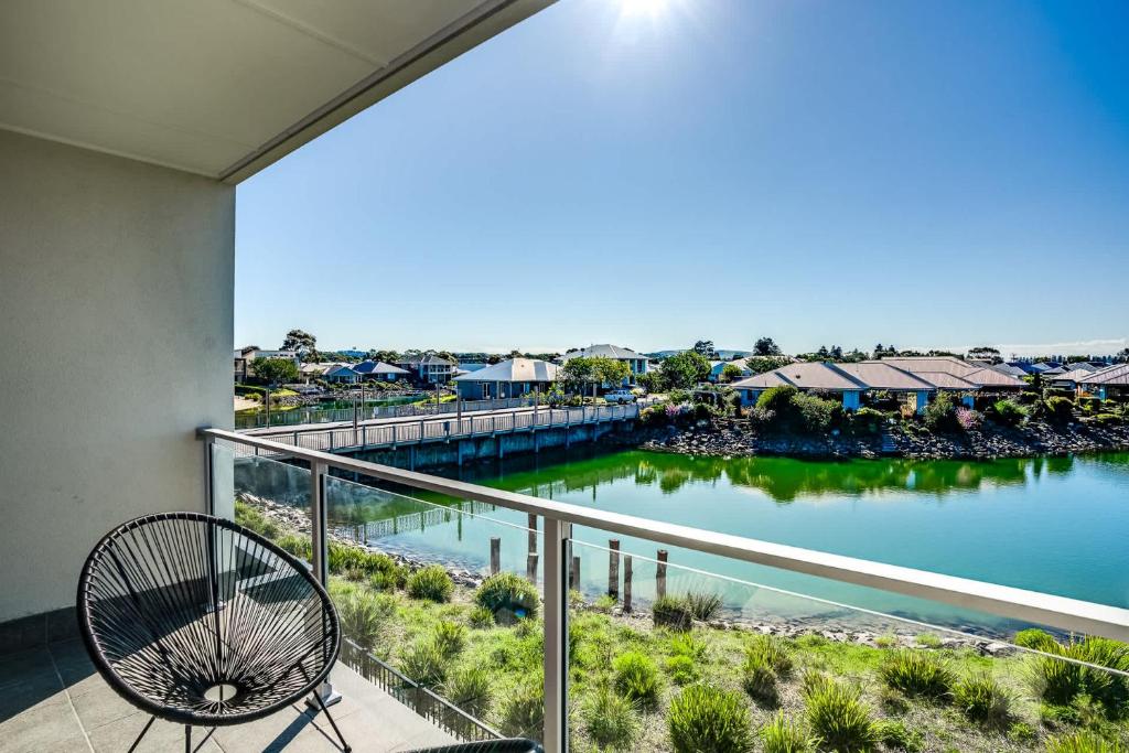 Un balcón con una silla y vista a un cuerpo de agua. en 4-13 Central Dr Victor Harbor-No Linen Included, en Victor Harbor