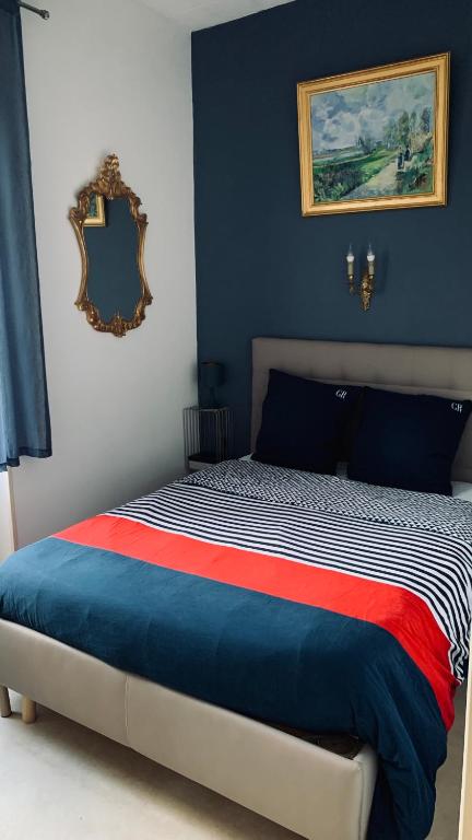 - une chambre avec un lit aux murs bleus et un miroir dans l'établissement La Garçonnière II, à Charolles