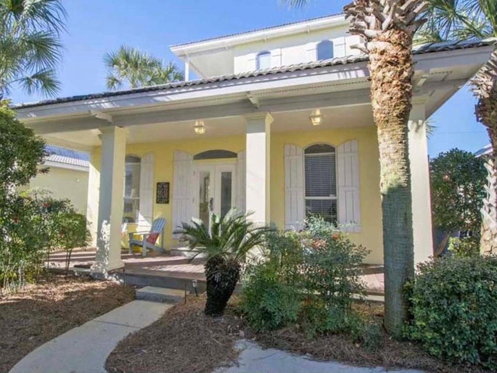 a yellow house with a palm tree in front of it at Changes In Latitude in Destin
