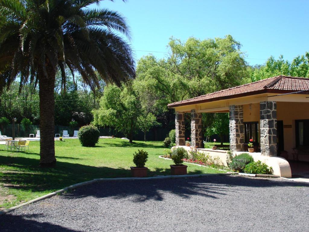 une maison avec un palmier et une véranda dans l'établissement Las Acacias - Posada de Campo, à Villa General Belgrano