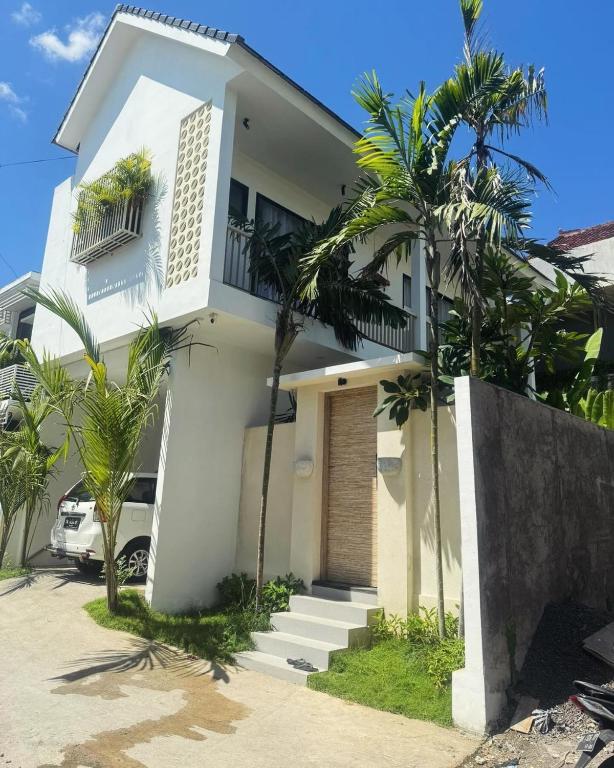 a white house with palm trees in front of it at Arthana Diamond in Nusa Dua