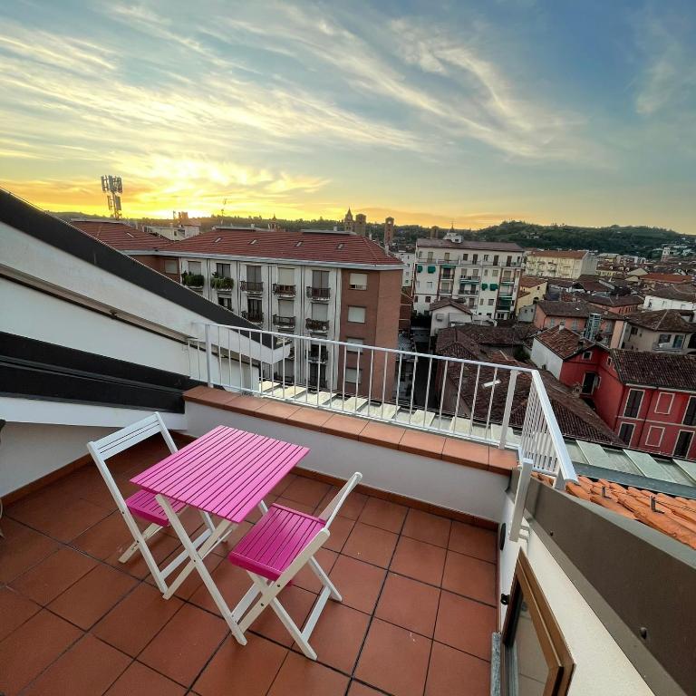 a pink table and two chairs on a balcony at La casetta sui tetti in Alba
