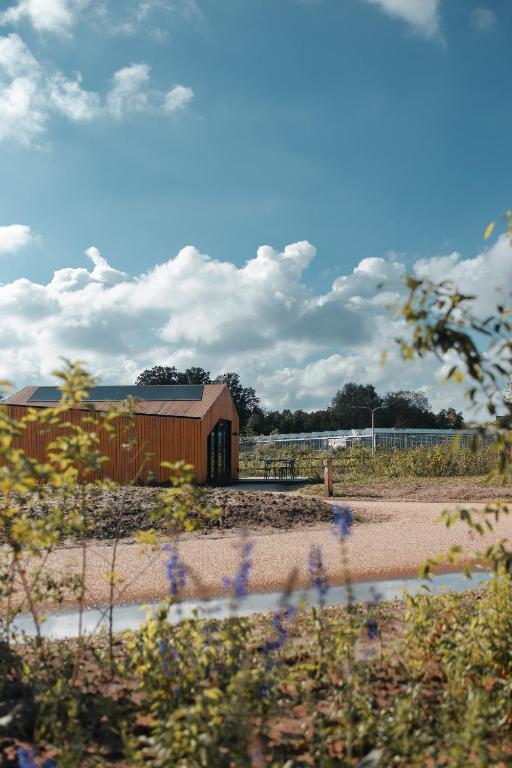a building in the middle of a field with flowers at Waterlinie Lodges in Utrecht
