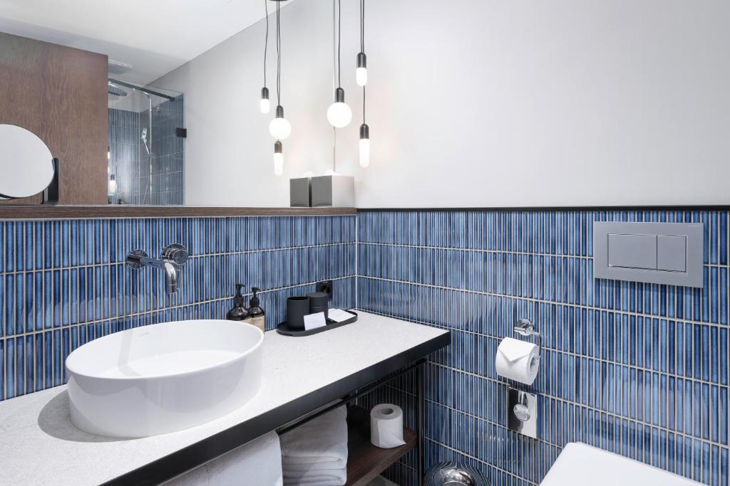 a bathroom with a white sink and blue tiles at The Yarn in Horgen