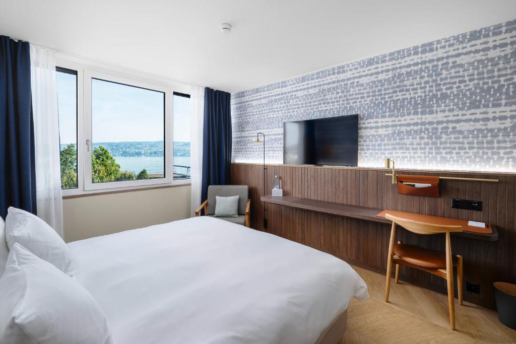 a hotel room with a bed and a desk and a tv at The Yarn in Horgen
