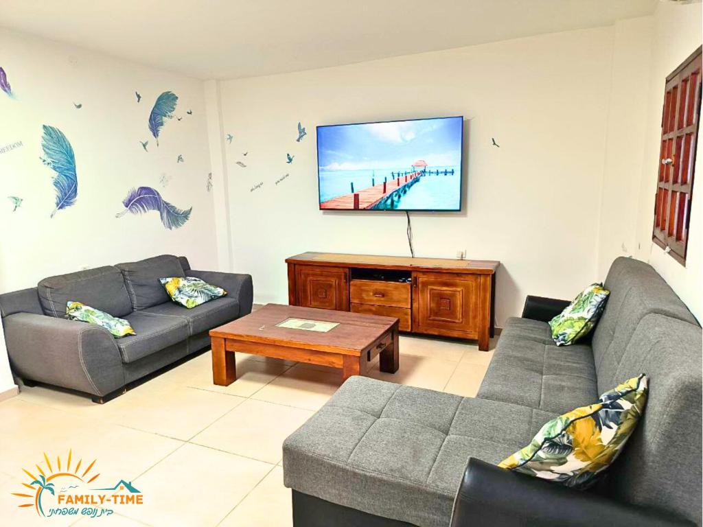 ein Wohnzimmer mit zwei Sofas und einem Flachbildfernseher in der Unterkunft Family-TIME בית פרטי לנופש משפחתי באילת in Eilat