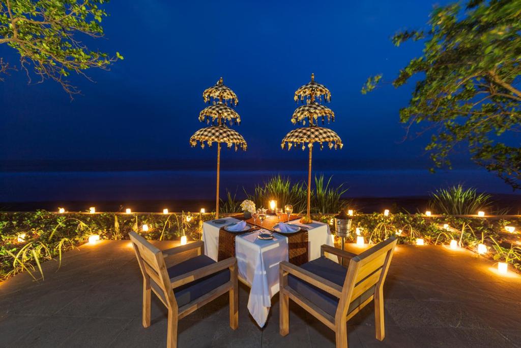 a dinner table with chairs and lights at night at Kelapa Retreat & Spa in Pulukan