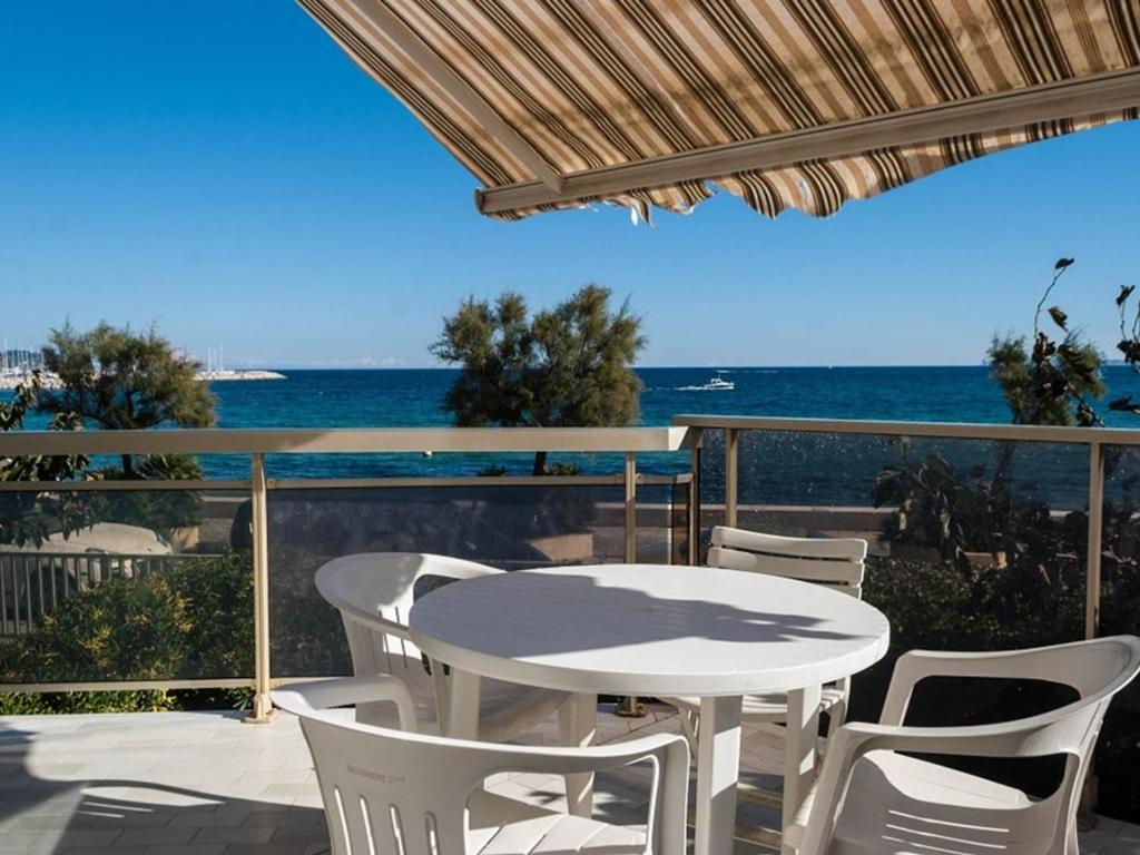 une table blanche et des chaises sur un balcon avec l'océan dans l'établissement T2 au Lavandou, 4 pers, accès plage, Wi-Fi, clim, parking - FR-1-803-62, au Lavandou