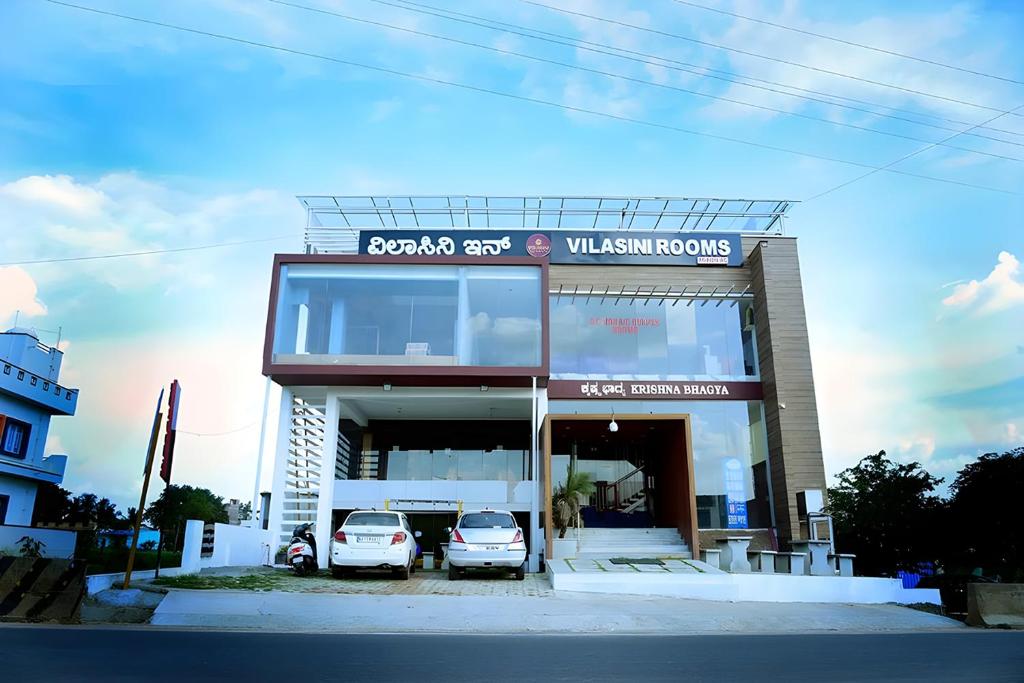 two cars parked in front of a building at Vilasini Inn in Maddūr