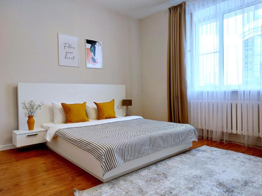 a bedroom with a bed with yellow pillows and a window at SPACE APART ASTANA просторные студии в центральном районе у монумента Байтерек in Astana