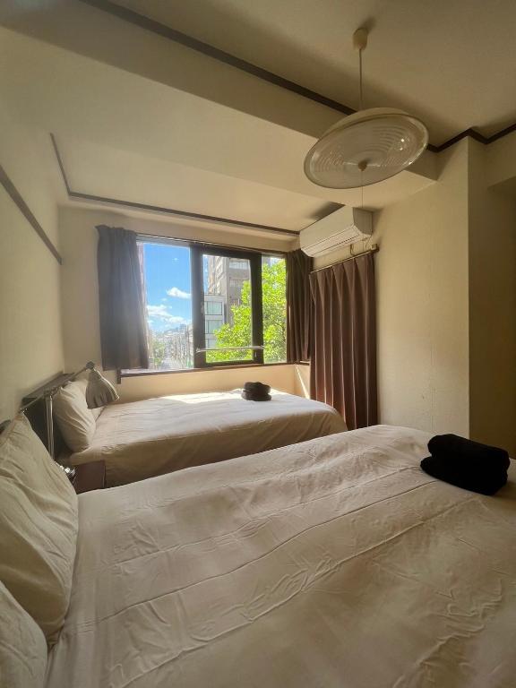 two beds in a room with a window at Yotsuya Matsumoto Hotel in Tokyo
