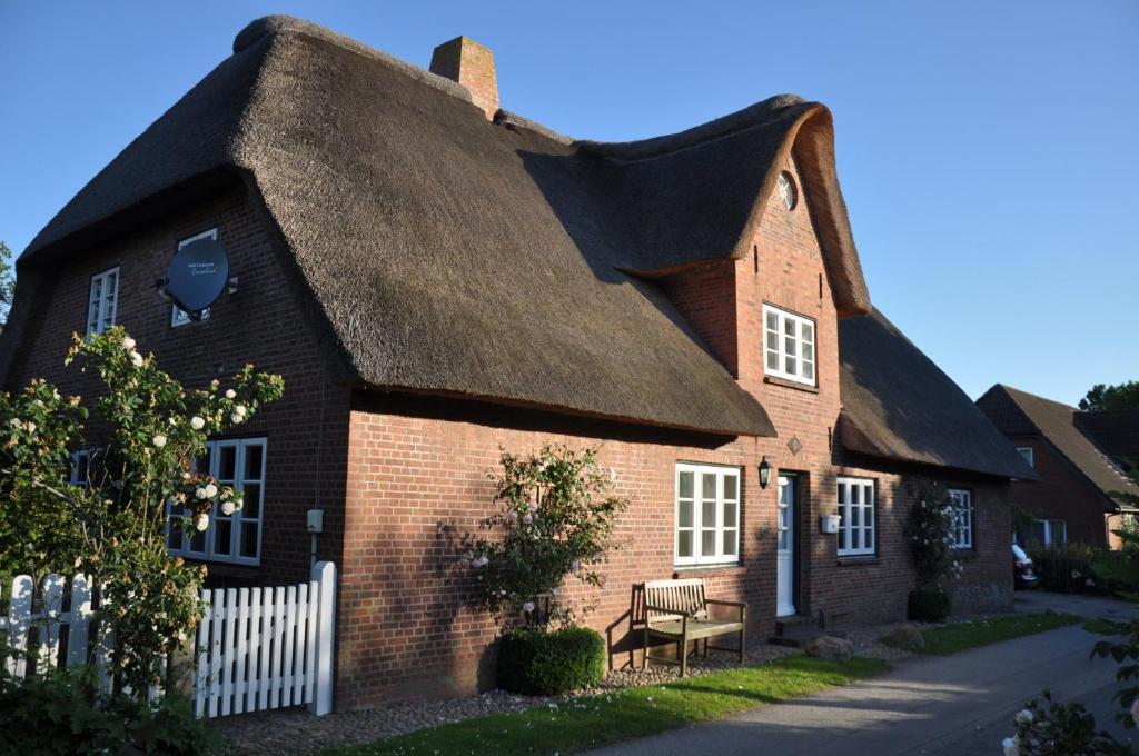 an old brick house with a thatched roof at Altes Standesamt Große Wohnung in Oldsum