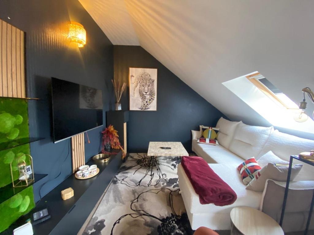 un salon avec un canapé blanc et une télévision dans l'établissement Le Roule, à Cherbourg en Cotentin